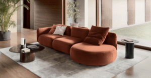 GINZA sofa designed by ELLEN BERNHARDT and PAOLA VELLA. GINZA  is a sofa system with sinuous and sensual shapes. Inspired by organic shapes reminiscent of 1970s design, it transforms any space into a warm and familiar landscape, spreading a pleasant sense of home comfort. Soft and enveloping lines recur in all the elements of the collection, which includes various modules that allow the creation of linear compositions, angular or unu-sual shapes, always characterized by the play of shapes and a cozy looking depth.