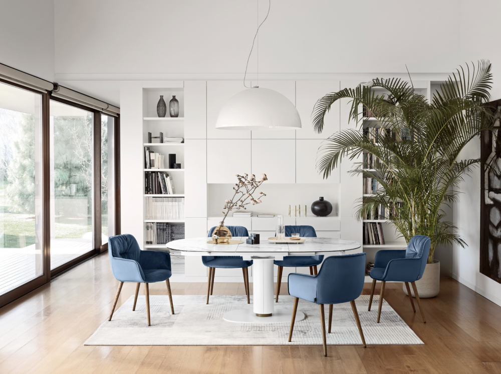 ELSON table  designed by GINO CAROLLO/Calligaris Studio. The design concept that underpins the ELSON table stems from a desire to tap into the sheer elegance of an oval, a fundamental shape in design research, and to balance it with the functional nature of a central base. When viewed from above, its two main parts (the base and the top) form two perfect concentric ovals which come together to create a triumph of geometric harmony. A pristine aesthetic which is both classic and contemporary at the same time, a pared-back design and faultless finishing touches make the ELSON table a timeless addition to any room, elevating any setting or furnishing style. An extendable table set on a central base with a completely automatic opening mechanism. The base comes in sheet metal, while the round-section column is detached from the heavy base plate by 3 cm, revealing a customizable inner strip that comes in 4 different colours. When the table needs to be opened, the extension leaf hidden underneath the two halves of the top rotates until it is perfectly lined up. One half of the top just needs to be pushed slightly for it to click into place. To close the table, you need to do the exact opposite.