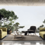 FLORIDA outdoor seating system by RODOLFO DORDONI, designed 2022.Natural teak is the wood chosen for FLORIDA to complement the mood of the 2020 Collection and design living compositions blurring the boundaries between indoors and outdoors.  The FLORIDA coffee table features feet in solid natural teak wood and a top with shaped edge in Pietra del Cardoso, in a brushed finish. Due to its mineral composition, Pietra del Cardoso is exceptionally compact and extremely weatherproof.