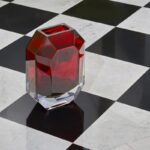 OCTOGONE vase. The signature of all Baccarat chandeliers, the octagonal tassel is here transformed into a red crystal vase, the signature colour of Baccarat obtained with pure gold. Like a delicately cut precious stone, the OCTOGONE vase is a true gem to embellish every ambiance. The clear-cut lines, corners and roundness are combined to reflect the light: a brilliant piece to illuminate the finest bouquets.