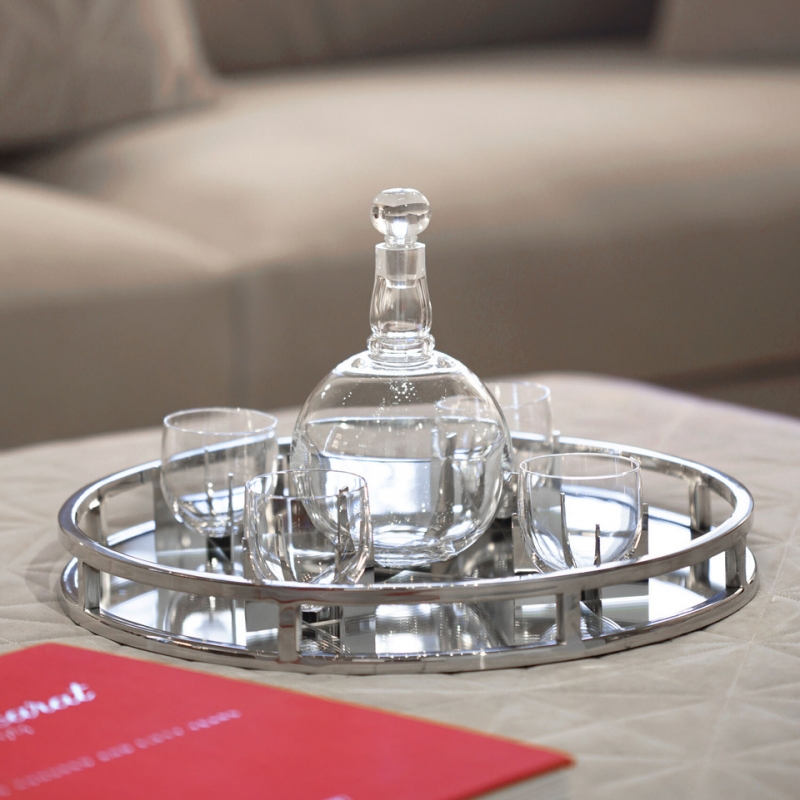 Baccarat - heritage PARAISON set. Baccarat presents an original re-issue of the PARAISON set created in 1931 by GEORGES CHEVALIER in the modernist mood of the Art Deco years. The set is composed of four glasses and a decanter. Crafted with amazing finesse, the set is a genuine masterpiece of expertise. The avant-garde design, combining the glitter of crystal with the austerity of metal, embodies the genius of GEORGES CHEVALIER, who took Baccarat into the modern era. The Maharajah of Indore, famous for his sumptuous orders placed with the leading names in luxury and his exquisitely fine taste, acquired this set in 1933 for his magnificent Art Deco-style Manik Bagh Palace. The timeless PARAISON set has retained its minimalist lines to glamorously highlight all occasions now and for years to come. This box holds a whiskey bottle and 4 PARAISON H√©ritage tumblers.