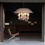 MARIE COQUINE chandelier by PHILIPPE STARCK, who has assembled a very peculiar inventory, as singular in scale as in concept. The components include the Clear crystal 12-light Z√©nith chandelier, 12 incandescent bulbs, 12 white Zenith lampshades, Baccarat‚Äôs signature red octagonal crystal, and an ivory canvas umbrella with a chestnut wood handle, signed by Baccarat and Starck upon the metallic band. Boasting an unforgettable visual impact, the surrealist and poetic chandelier showcases the iconoclastic PHILIPPE STARCK‚ÄôS uninhibited humor and originality. More than a light source, MARIE COQUINE is a veritable sculpture and contemporary art piece. A limited edition MARIE COQUINE FLOOR lamp is also a true collector‚Äôs item.