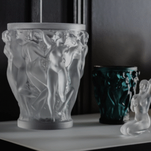 BACCHANTES  vase designed by REN√â LALIQUE. In 1927, REN√â LALIQUE‚Äôs boundless imagination and creative genius lead to the creation of the BACCHANTES vase.The iconic design features the young priestesses of Bacchus with their voluptuous beauty and curves. A work of unparallel beauty, the splendor and sensuality of the vase continue to leave admirers spellbound.Since its original release, it has been a staple in the Lalique collection and has become a lasting symbol of Lalique‚Äôs celebrated style.The extra large version of this iconic vase is intended for collectors worldwide. Its meticulous detailing, carved by hand, adds a playful use of light and dimension.
