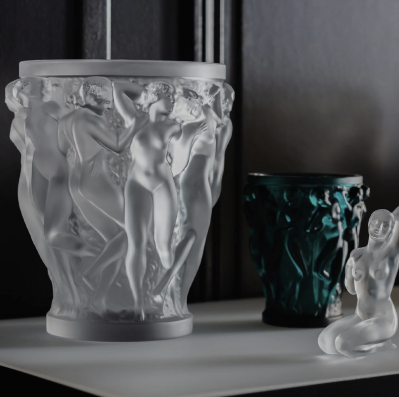 BACCHANTES  vase designed by REN√â LALIQUE. In 1927, REN√â LALIQUE‚Äôs boundless imagination and creative genius lead to the creation of the BACCHANTES vase.The iconic design features the young priestesses of Bacchus with their voluptuous beauty and curves. A work of unparallel beauty, the splendor and sensuality of the vase continue to leave admirers spellbound.Since its original release, it has been a staple in the Lalique collection and has become a lasting symbol of Lalique‚Äôs celebrated style.The extra large version of this iconic vase is intended for collectors worldwide. Its meticulous detailing, carved by hand, adds a playful use of light and dimension.