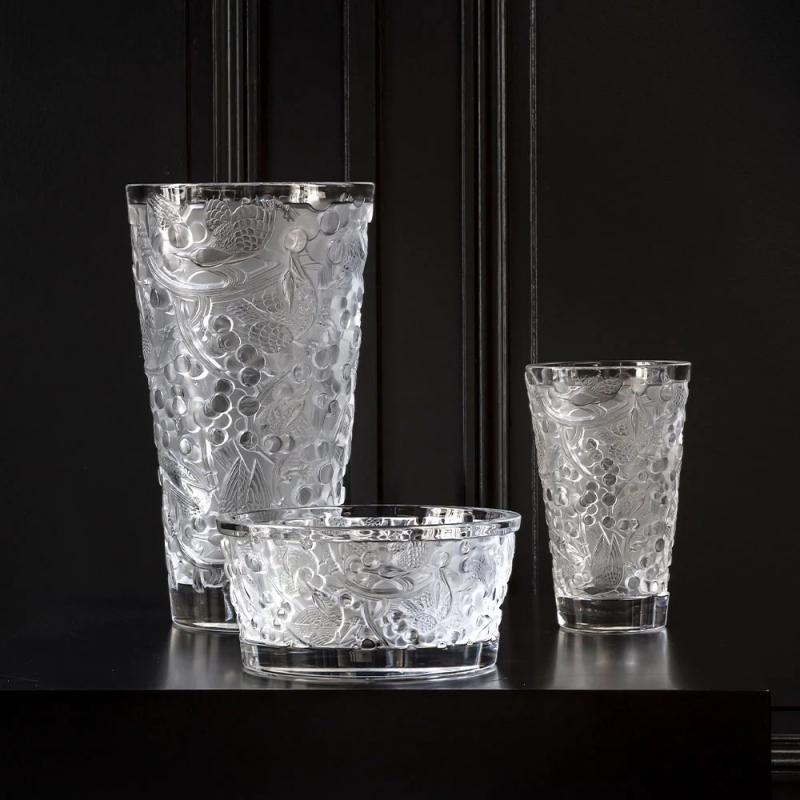 MERLES ET RAISINS bowl. In 1928, RENÉ LALIQUE designed the MERLES & RAISINS decorative panels, originally in created in pressed glass on a silver background and adorned the Cuban mahogany woodwork of the legendary Orient Express. Today, the Lalique Studio reinterprets this emblematic creation, in new expressions through vases and a bowl. The precious cultural heritage of the House thus comes to life in very contemporary shapes. Blackbirds with finely chiseled plumage indulge in an abundance of sweet grapes while the vines create an exceptional rhythm throughout a perfectly balanced composition. The richness of the decor conveys a sensation of profusion and of abundance. Highlighted by the purity of satin-finished crystal, signature of the House, these decorative objects brilliantly illustrate the timeless character of Lalique creations.