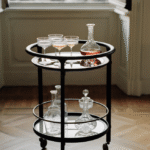 DUO bar trolley by ROBERTO LAZZERONI. DUO bar trolley is the wheeled bar cart with solid ash wood frame in various finishes. The upper glass top can be clear, bronzed or smoked; the lower top can be marble, back-painted glass or multilayer veneered ash in the same finish chosen for the frame. The bronzed brass details create a pleasing contrast with the solid wood frame.
